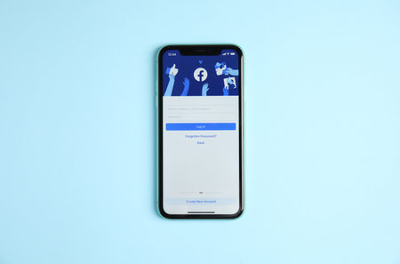 MYKOLAIV, UKRAINE - JULY 10, 2020: Iphone 11 with Facebook app on light blue background, top viewのeditorial素材