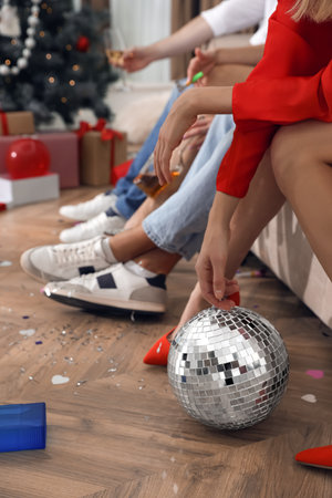 People sitting on sofa in messy room after New Year party, closeup of legsの写真素材