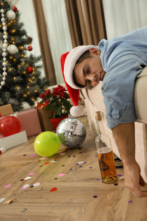 Man sleeping on couch in messy room after New Year partyの写真素材