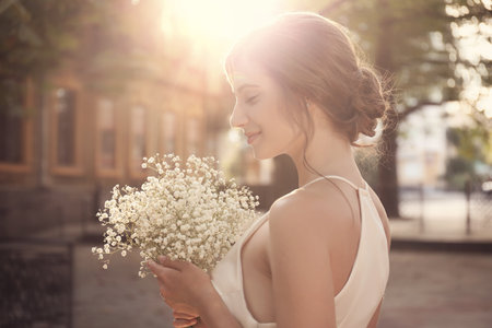 Gorgeous bride in beautiful wedding dress with bouquet outdoorsの写真素材