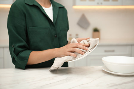 Woman wiping plate with towel in kitchen, closeupの写真素材