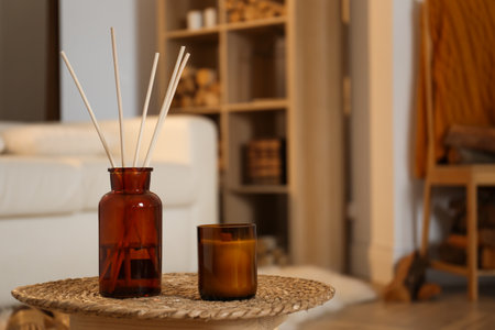 Aromatic reed air freshener and candle on wicker tray in room. Space for textの写真素材