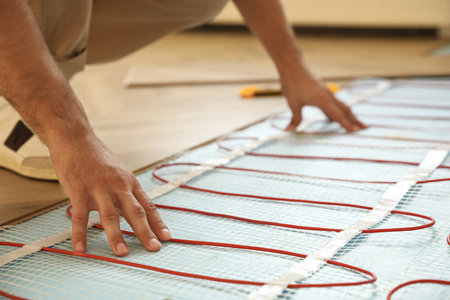 Professional worker installing electric underfloor heating system indoors, closeupの写真素材