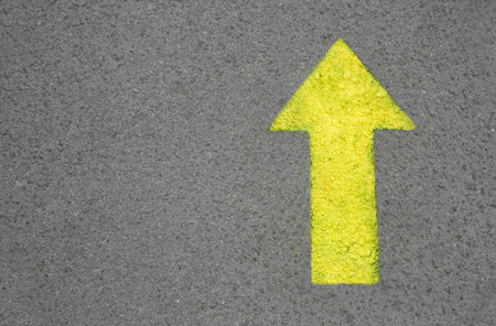Yellow arrow painted on asphalt, top view. Space for textの写真素材