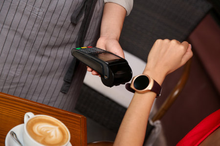 Woman making payment with smart watch in cafe, closeupの写真素材