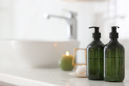 Green soap dispensers on countertop near sink in bathroom. Space for textの写真素材