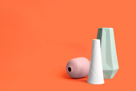 Stylish empty ceramic vases on orange background, space for textの写真素材