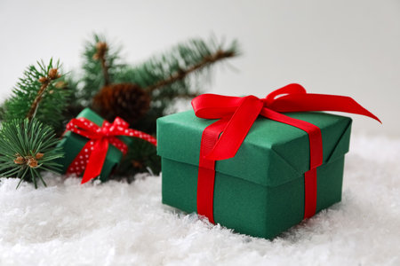 Christmas gift box with red bow and fir tree branches on snow. Space for textの写真素材