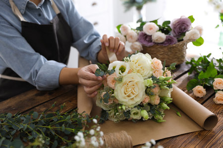 Florist making beautiful wedding bouquet at wooden table, closeupの写真素材