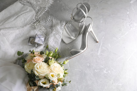 Flat lay composition with white wedding dress and bouquet on gray marble table. Space for textの写真素材