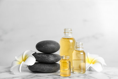 Beautiful composition with aroma oil and spa stones on white marble tableの写真素材