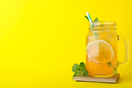 Delicious iced tea with lemon and mint on yellow background. Space for textの写真素材