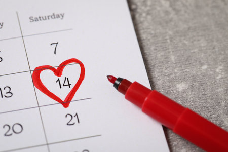 Calendar with marked Valentine's Day and red felt tip pen on gray table, closeupの写真素材