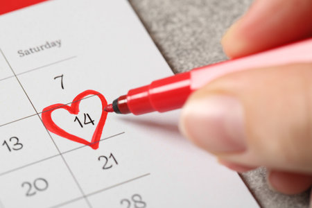 Woman marking Valentine's Day on calendar on gray table, closeupの写真素材