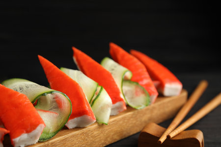 Cut crab sticks with cucumber on wooden board, closeupの写真素材