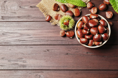 Fresh sweet edible chestnuts on brown wooden table, flat lay. Space for textの写真素材