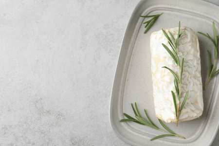Delicious fresh goat cheese with rosemary on light gray table, top view. Space for textの写真素材