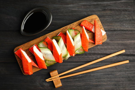 Crab sticks with cucumber and soy sauce served on dark wooden table, flat layの写真素材