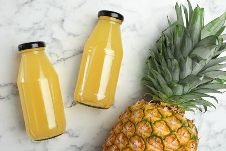 Delicious pineapple juice and fresh fruit on white marble table, flat layの写真素材