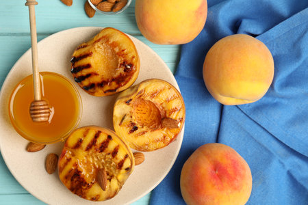 Delicious grilled peaches with honey and almonds on light blue wooden table, flat layの写真素材