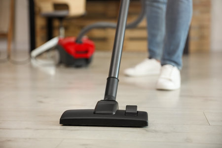 Young man using vacuum cleaner at home, closeupの写真素材