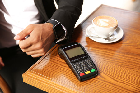Man making payment with smart watch in cafe, closeupの写真素材