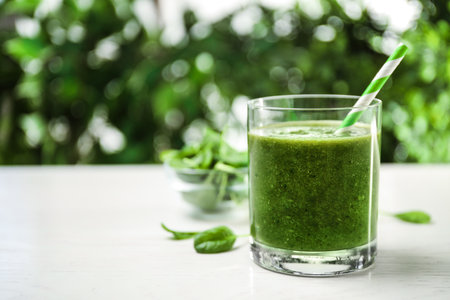 Delicious fresh green juice on white table, space for textの写真素材