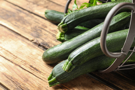Basket with green zucchinis on wooden table, closeupの写真素材