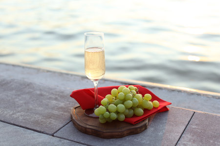 Glass of champagne and fresh grapes served near the riverの写真素材
