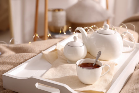 White tray with ceramic tea set on bedの写真素材