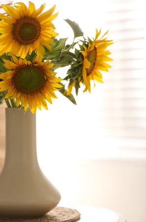 Vase with beautiful yellow sunflowers on table in roomの写真素材