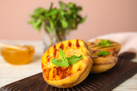 Delicious grilled peaches with mint on wooden board, closeupの写真素材
