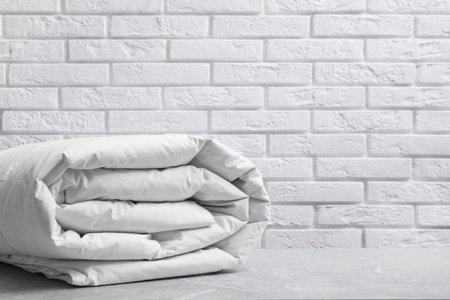 Soft folded blanket on light gray table, closeup. Space for text