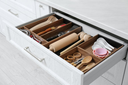 Open drawer with utensil set indoors. Order in kitchen