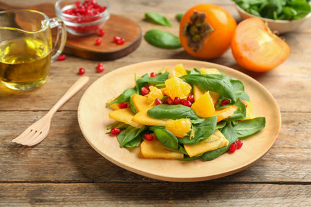 Delicious persimmon salad with pomegranate and spinach on wooden tableの写真素材