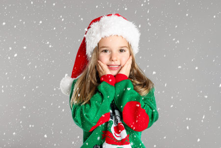 Cute child in Santa hat under snowfall on gray background. christmas celebrationの写真素材