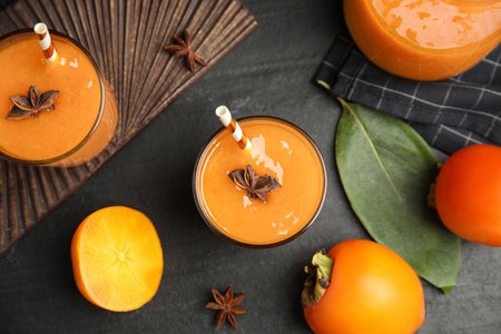 Tasty persimmon smoothie with anise and fresh fruits on black table, flat layの写真素材