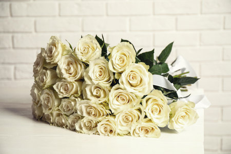 Luxury bouquet of fresh roses on table near white brick wallの写真素材