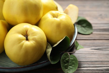 Fresh ripe organic quinces with leaves on wooden table, closeupの写真素材
