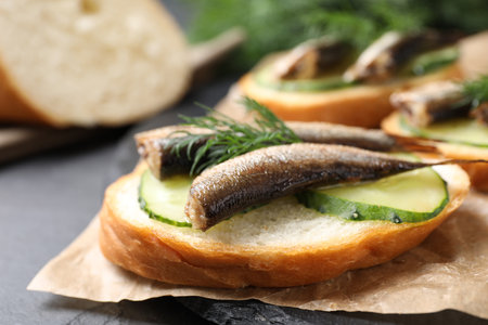Delicious sandwich with sprats, cucumbers and dill on slate board, closeupの写真素材