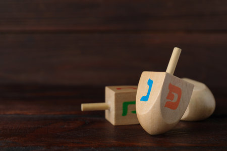 Hanukkah traditional dreidel with letters Nun and Pe on wooden table. Space for textの写真素材