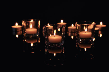 Burning candles in glass holders on dark backgroundの写真素材