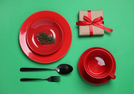 Beautiful Christmas table setting with gift on green background, flat layの写真素材
