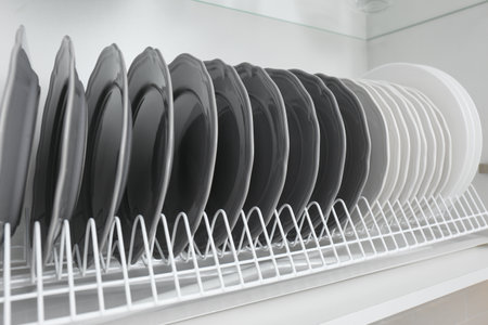 Drying rack with clean plates in kitchen cabinet, closeupの写真素材