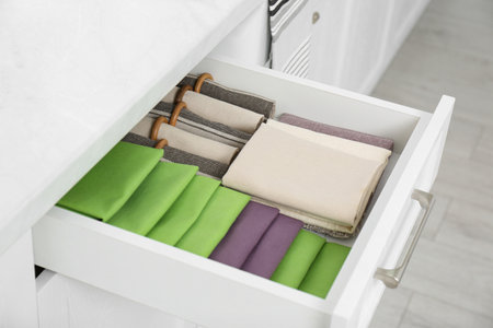 Open drawer with different folded towels and napkins in kitchenの写真素材