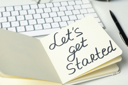 Notebook with phrase Let's Get Started and keyboard on white tableの写真素材