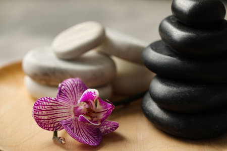 Spa stones and orchid flower on wooden plate, closeupの写真素材