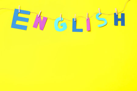 Thread with pinned word ENGLISH on yellow background, top view. Space for textの写真素材