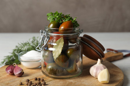 Pickling jar with fresh ripe tomatoes on white tableの写真素材