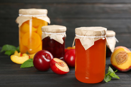 Glass jar of peach jam and fresh fruits on black wooden tableの写真素材